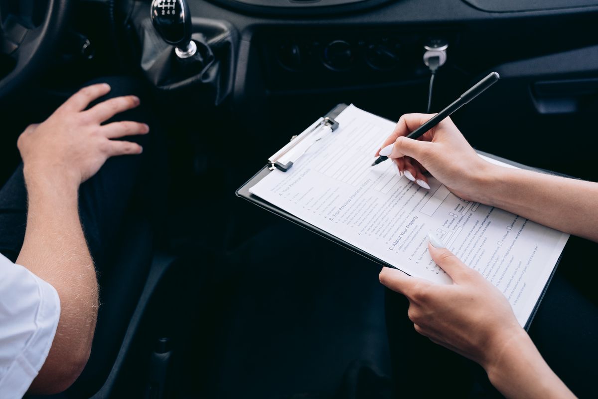 Insurance claim form being filled out on a clipboard inside a vehicle